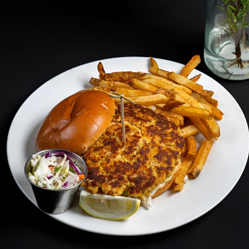 McClellan's Fish and Chicken crab cake sandwich with fries, coleslaw, and a lemon wedge.