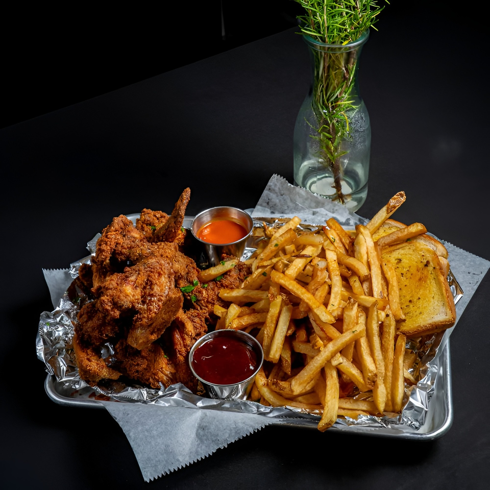 A tray of McClellan's fried chicken, french fries, garlic toast, and two dipping sauces.